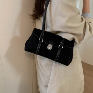 Detail of black suede hobo bag with silver buckle worn over a beige coat