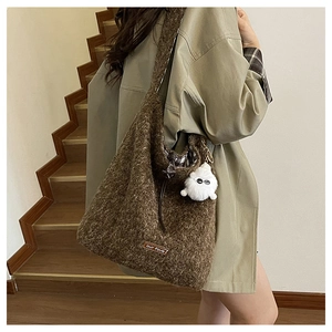 Detail of soft brown plush tote bag with cartoon charm and leather brand tag