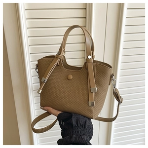 Close-up of brown woven bucket bag with leather handle and metal buckle detailing
