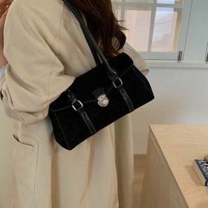 Detail of black suede shoulder bag featuring silver buckle and contrast white stitching