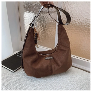 Detailed view of dark brown suede crescent bag with leather strap and wooden bead accessory
