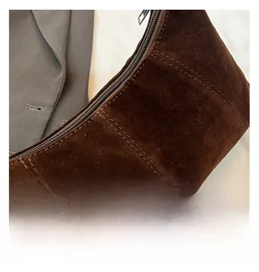 Detailed close-up of dark brown wax leather crescent bag showing double stitching and metal zipper