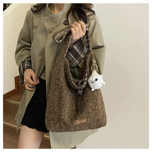 Detail of brown faux fur tote bag showing plaid lining and white pom-pom charm