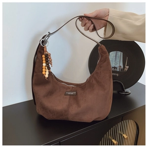 Close-up of brown suede hobo bag with vintage wooden bead tassel and leather label