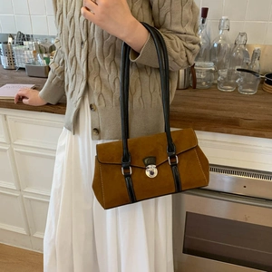 Detail of vintage brown suede shoulder bag with black leather straps and metal twist lock