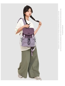 Detail view of the purple multi-compartment backpack showing the drawstring closure and flap
