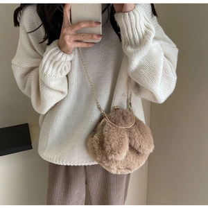 Gros plan d'un sac bandoulière en peluche marron avec chaîne dorée et fermoir métal