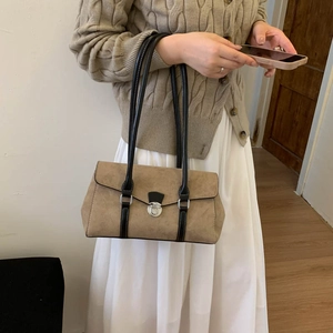 Close-up of khaki suede shoulder bag featuring silver metal lock and black leather straps