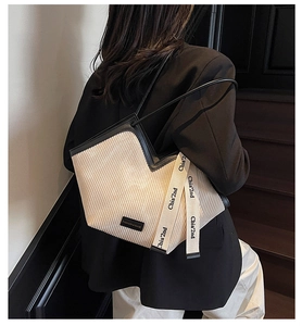 Detail of pleated tote bag with black trim and Chia'2nd logo straps on a shoulder bag