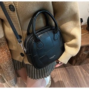 Detail of a black faux leather crossbody bag featuring unique square patchwork texture