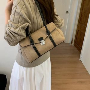 Khaki suede shoulder bag with black leather straps styled on a cable knit sweater