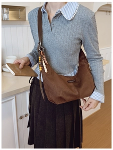 Detail of dark brown suede hobo bag with colorful wooden beads and leather strap charm