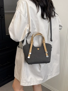 Retro grey woven bucket bag with brown handles carried by model in a grey coat