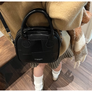 Detail of a black leather crossbody bag featuring unique texture and sturdy handle