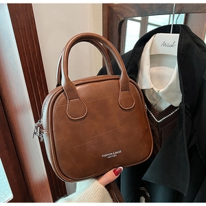 Detail of brown leather handbag with contrast stitching and Fashion & Bags text logo