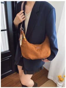 Brown faux suede crescent bag detail with ethnic beaded charm and leather logo patch