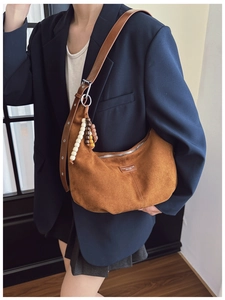 Close-up of brown suede hobo bag featuring a retro wooden bead charm and leather strap
