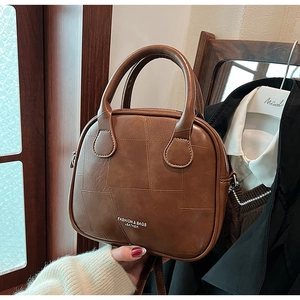 Close-up of vintage brown patchwork handbag with geometric stitching and metal zipper detail