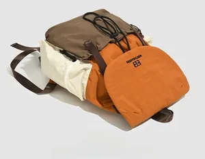 Detail of color-blocked nylon backpack with orange flap and drawstring closure system