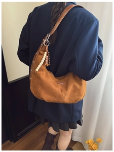 Detail of a brown suede half-moon bag featuring vintage wooden beads and logo leather patch