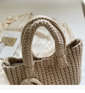 Détail du sac à main beige en tricot fait main montrant la texture du crochet et des anses