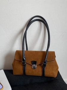 Brown suede shoulder bag with black leather straps and metal clasp in a retro pillow style