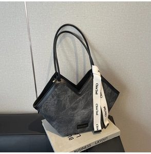 Detail of grey corduroy tote bag featuring black leather trim and V-shaped opening design