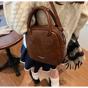 Close-up of retro brown leather square bag with white logo print on wooden table