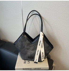Detail of grey corduroy tote bag with black leather trim and V-shaped opening on a book