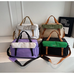 Detail view of large travel bags in four colors arranged on a white step display