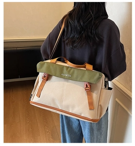 Rear view of a model carrying the large ivory and olive green canvas travel bag