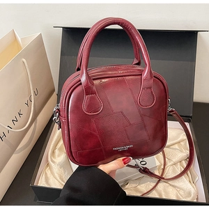Detail of burgundy leather handbag with patchwork texture in a premium gift box