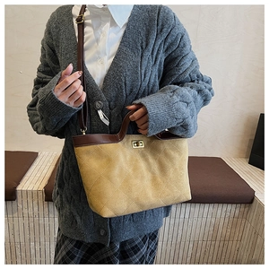 Close-up of mustard yellow quilted tote bag with brown leather handles and gold lock