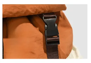 Detail of durable black plastic buckle on orange nylon outdoor travel backpack