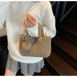 Close-up of handmade khaki knit handbag showing woven texture and mini round coin purse