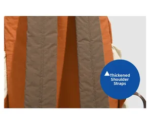 Detail view of thickened padded shoulder straps on an orange nylon travel backpack