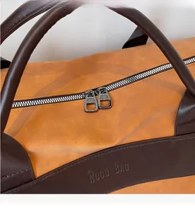 Detail view of smooth silver dual zippers and logo embossing on the leather travel bag
