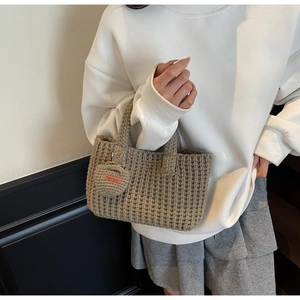 Close-up of hand-woven bucket bag featuring a handmade tag and chunky knit texture