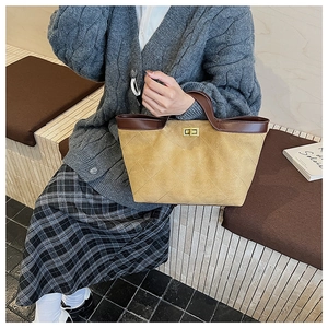 Detail of yellow quilted suede tote bag with brown leather handles and gold metal twist lock