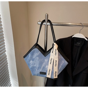 Blue corduroy tote bag detail with v-shaped opening and decorative ribbon on metal stand
