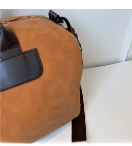 Detailed close-up of brown frosted travel bag featuring premium leather handles and metal zipper
