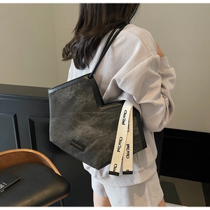 Detail of grey corduroy tote bag showing fashion leather label and cream branded strap