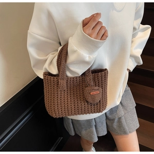 Detail of brown handmade crochet tote bag featuring heart pendant and handmade tag