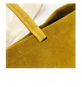 Detailed macro view of yellow suede tote showing fine stitching on smooth leather handle