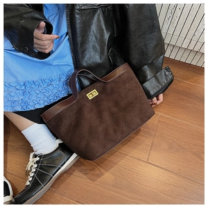 Close-up of brown suede tote bag featuring quilted pattern and gold metal twist lock