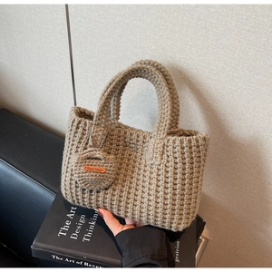 Detail of hand-knitted tote bag with crochet texture and Hand Made leather label