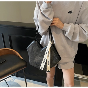 Detail of black corduroy tote bag with white canvas strap featuring branded lettering