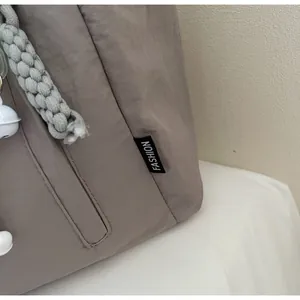 Detail of coffee grey nylon tote bag with fashion tag and woven rope decoration
