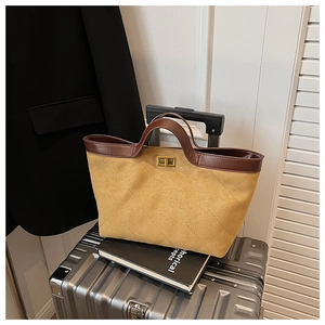 Detail of yellow quilted suede tote bag with brown leather trim and golden twist lock