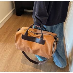 Caramel suede travel bag detail with dark brown leather handles and adjustable strap